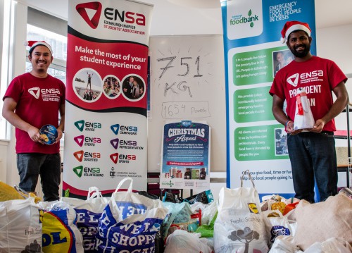 Two ENSA members standing next to a food bank collection