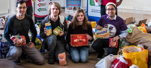 Four ENSA volunteers kneeling next to a food bank collection
