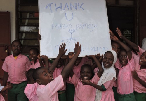 A group of children holding up a sign thanking Mikoko Pamoja