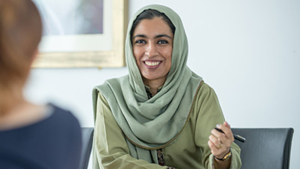 smiling student wearing a hijab and holding a pen