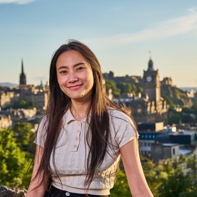 Student smiling with Edinburgh landscape in the background