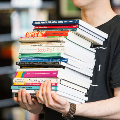 Student carrying large pile of books