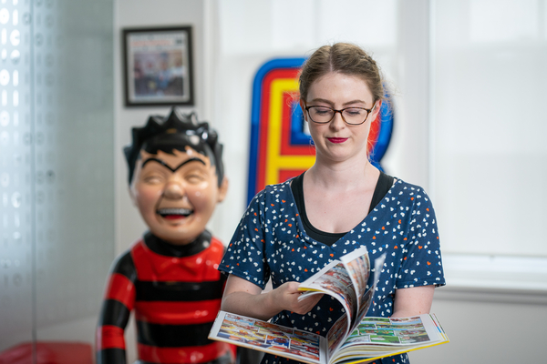 An image of our postgraduate alumni, Grace, looking at her book for the check when you need to apply guide link. 