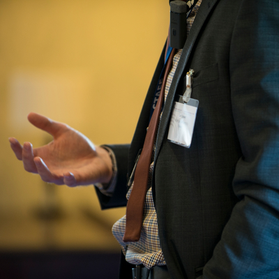 Close up of a man in a suit with a name tag.