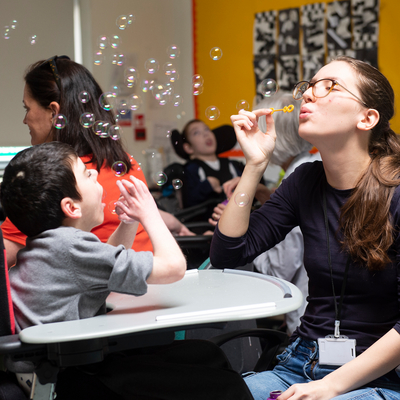 Student nurse blowing bubbles with a child