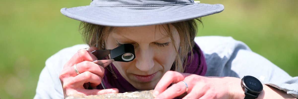 Edinburgh Napier student examining rocks with a geologist's hand lens during a field trip to St Abbs nature reserve. 