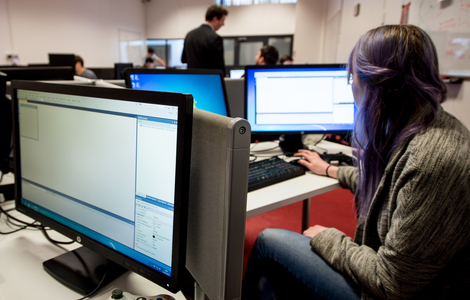 Computing student working in front of dual monitors