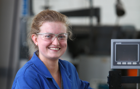 Smiling student in front of engineering equipment