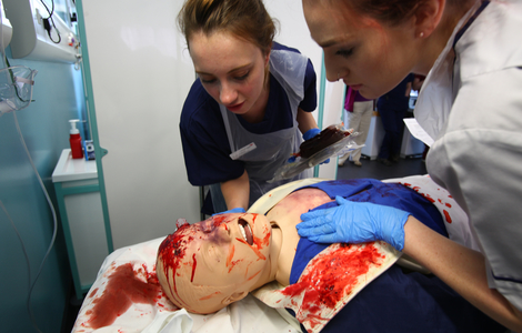 Student nurses working on a bloody mannequin in the Clinical Skills room