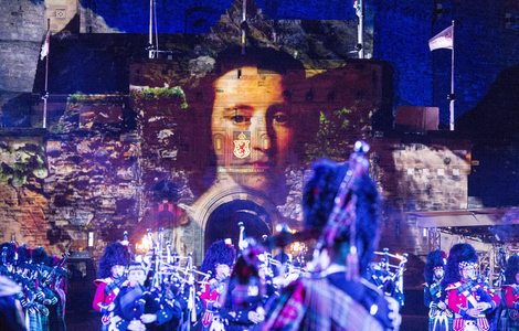Royal portrait painting projected onto Edinburgh Castle behind performers at Edinburgh Military Tattoo