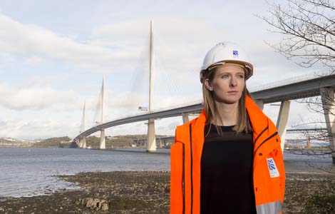 student in high visibility work gear standing beside the queensferry crossing bridge