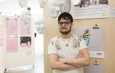 MSc Creative Advertising student with his arms crossed standing beside a project board