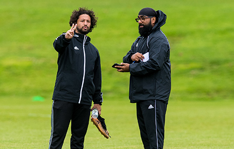 Two men talking at Football practice on a grass pitch
