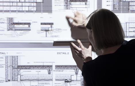 Back of an Architect pointing to part of projected building plans