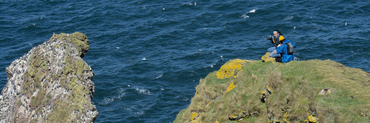 Two students photographing wildlife on the cliffs at St Abbs