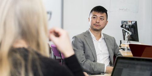 Zhongdong Niu, Lecturer in Accounting Financial Services and Law is sitting listening to a woman speak