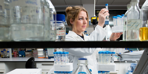 Student holding up a tube to analyse at work in a laboratory