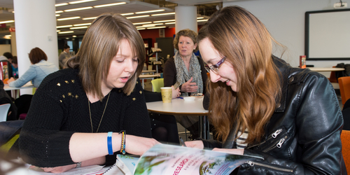 Social Science students studying a textbook in the university library
