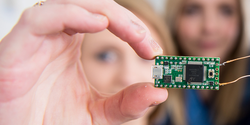 Close up of micro electronic circuit board held up to the camera by a student's hand