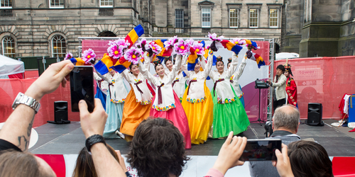 Group of dancers dressed in brightly coloured dresses in Edinburgh city centre