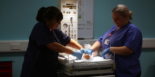 Student nurses attend the beside of a neo natal mannequin