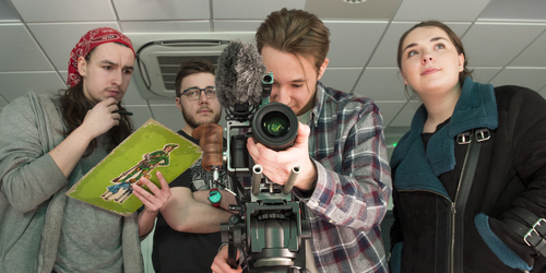 Four Television students standing behind a camera at work in the studio