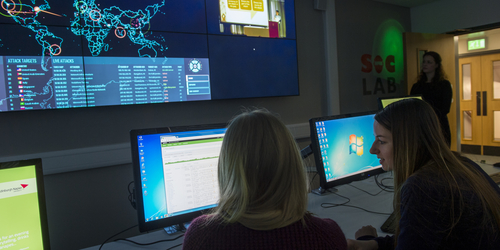 Two female students in the SOC lab looking at computers