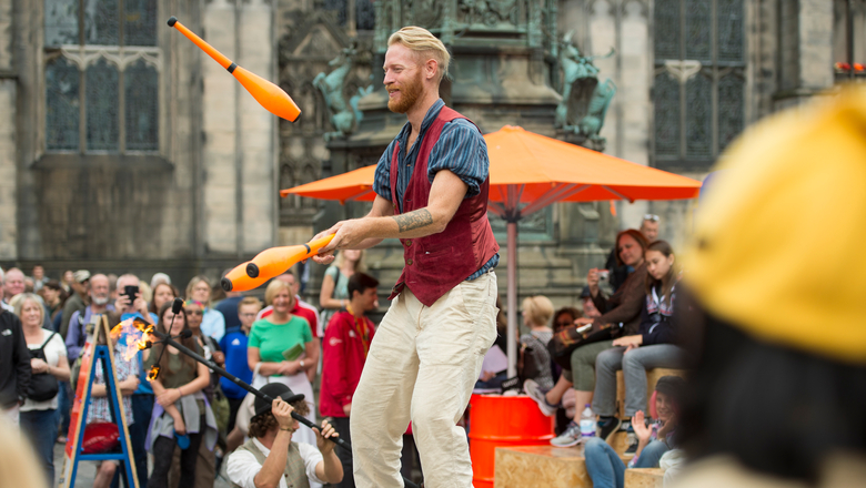Juggler performing to a large crowd on the Royal Mile during the Edinburgh Fringe Festival.