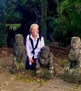 Gerri Matthews-Smith kneeling on the ground next to three monkey sculptures