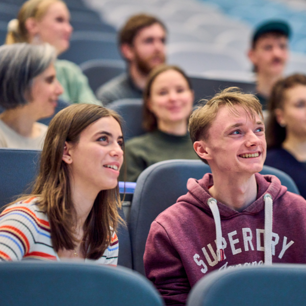 Students seated in a lecture theatre using laptops during a class.