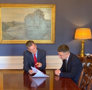 Euan and Cameron in seated around a table, looking at a document 