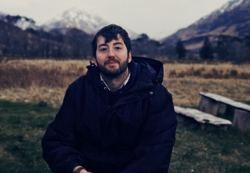 Product Design alumnus Jamie Boult crouching down with the Scottish Highlands in the background