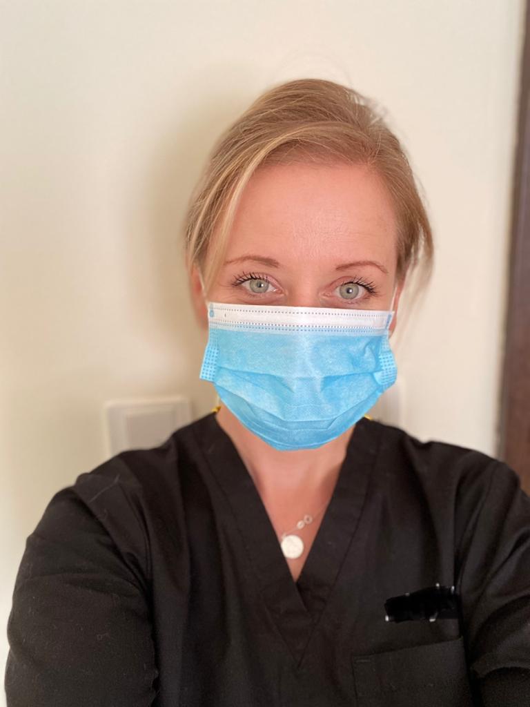 Rebecca Gates looking into the camera wearing a face mask