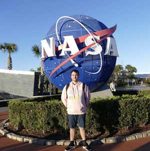 Adam Smith standing in front of a 3D NASA logo at their headquarters in America