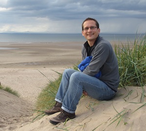 Craig Weldon sitting on a sandy beach 