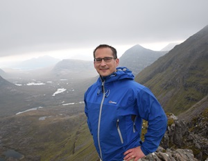 Craig Weldon hillwalking, with a range of mountain peaks in the background 