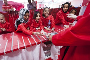 A group of school children, all wearing red safety bibs, taking part in a science experiment 