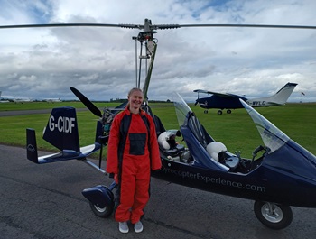Maria wearing a red jumpsuit, standing in front of a gyrocopter at Perth Airport
