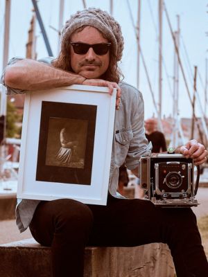 Cameron J Laing posing with his camera and framed photo