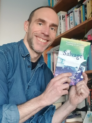 Mark Baillie holding his book, Savage