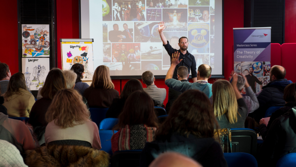 Alumnus standing in front of a seated audience giving a lecture