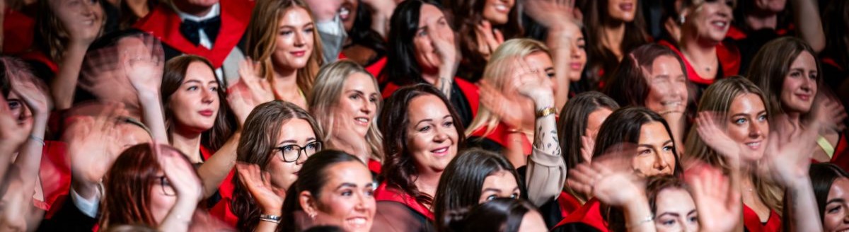 Students waving and cheering at graduation ceremony