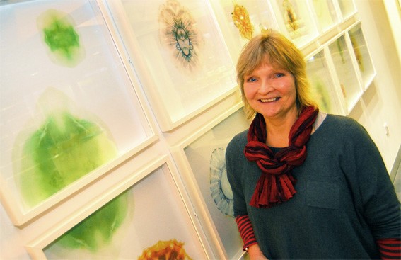 Susanne Ramsenthaler standing next to a patterned wall, smiling at the camera 