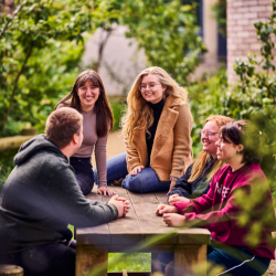 A group of people sitting on a picnic bench surrounded by foliage