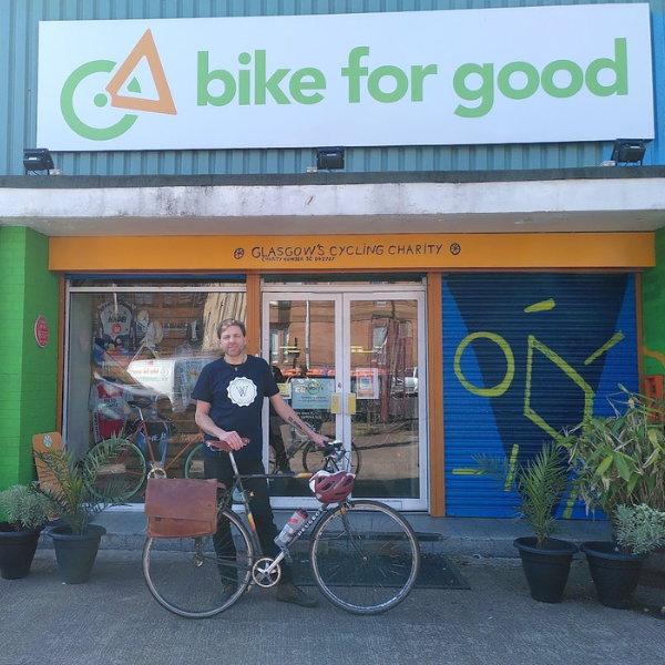 Alumnus Gregory Kinsman-Chauvet standing in front of Bike for Good, cycling charity