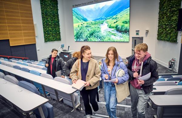 Three students smiling and chatting as they ascend the stairs at Edinburgh Napier University's new Riady lecture theatre.