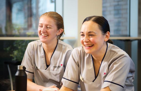 Two Edinburgh Napier Nursing students laughing in the café area of the Sighthill campus.  