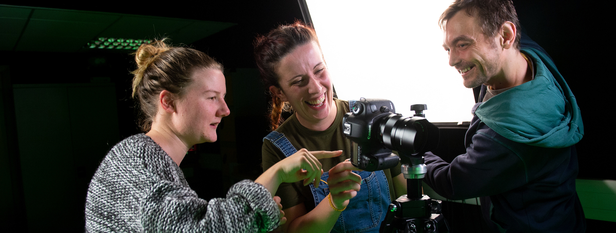 Three students changing a camera's settings