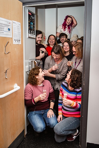 People gather in a toilet to celebrate the end of the Bloody Big Project