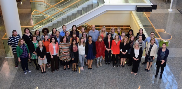 A group photo of around 30 members of the ACHIEVE study team standing in a foyer